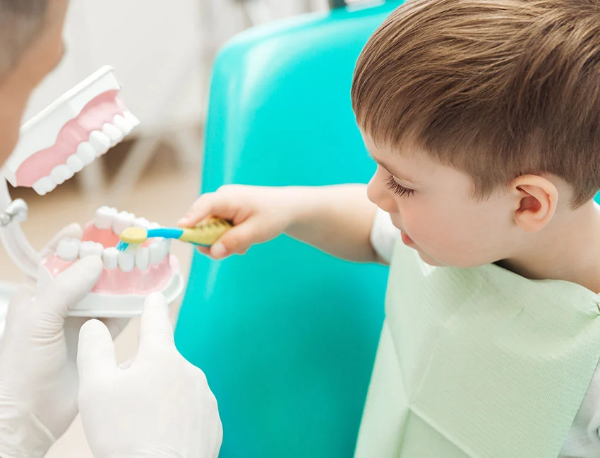 Dentist showing kid how to brush teeth